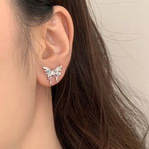 Detailed view of silver butterfly earring with colorful gemstones worn on the ear