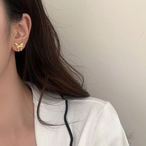 Close-up of elegant gold bow earrings with zircon stones on female ear model