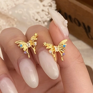 Elegant gold bow earrings with colorful zircon stones shown held by fingers