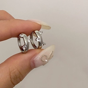 Close-up of small silver hoop earrings with sparkling cubic zirconia on a neutral background