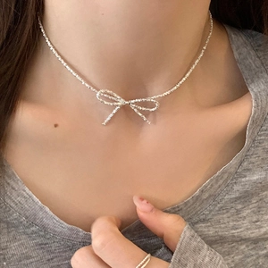 Sparkling silver bow pendant necklace with delicate chain on model neck