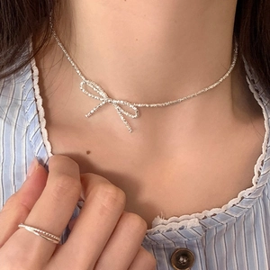 Detailed close-up of a silver bow pendant necklace and matching minimalist double-layer ring