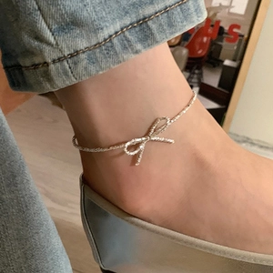 Silver bow pendant necklace on ankle view with delicate chain and minimalist style
