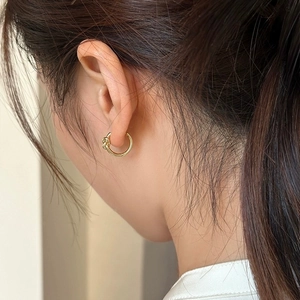 Detail of elegant gold knot hoop earring worn on model for a minimalist fashion look