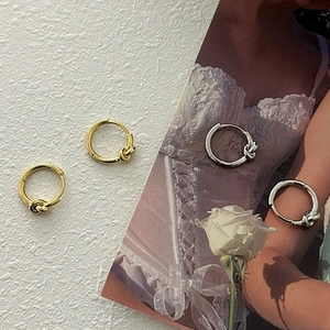 Macro detail of geometric knot hoop earrings in polished gold and silver finishes