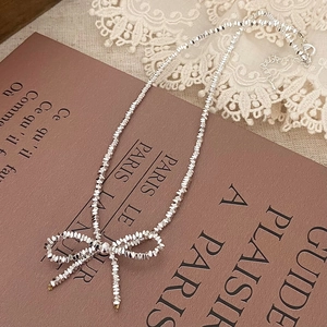 Detail of silver beaded bow necklace featuring faceted beads and an adjustable lobster clasp