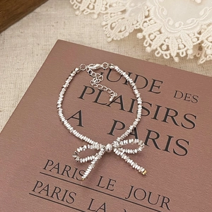 Macro detail of a silver beaded bow pendant necklace with adjustable lobster clasp