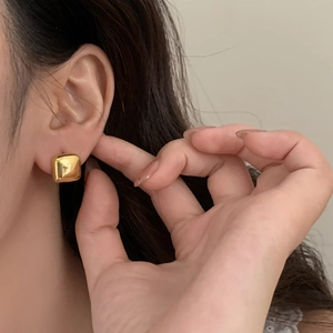 Minimalist gold geometric square stud earrings on a model with a polished finish