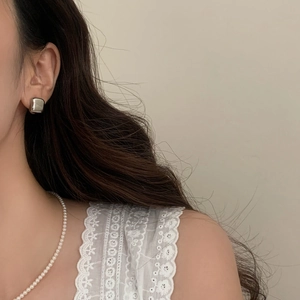 Polished silver geometric square stud earrings shown on model with white lace outfit