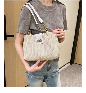 Detailed straw shoulder bag view featuring gold chain straps and metal twist lock closure