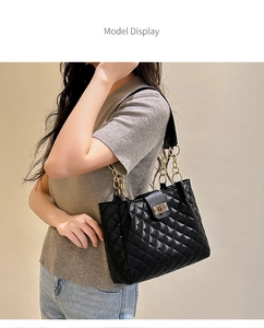 Close-up of black quilted leather shoulder bag with golden chain and metallic turn-lock