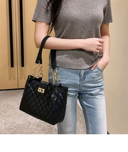 Detail of black quilted shoulder bag featuring gold metal twist lock and chain strap