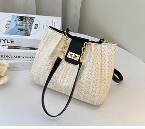 Close-up of beige woven straw texture with black leather trim and golden metal chain link