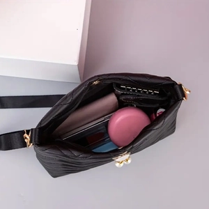 Top view of quilted black leather crossbody bag showing interior capacity and pearl charm
