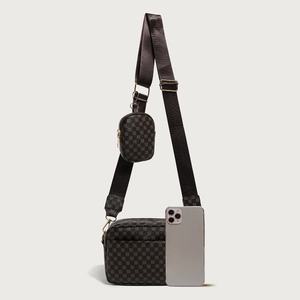 Detail view of printed crossbody camera bag showing texture and size reference to phone