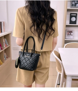 Dettaglio della borsa a secchiello nera trapuntata con mini borsa su outfit kaki