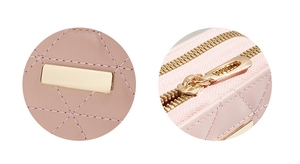 Macro detail of pink quilted leather texture with gold logo plate and metal zipper