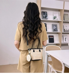 Dettaglio borsa tote in paglia con manici in pelle nera e mini borsellino rotondo abbinato