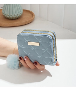 Close-up of a light blue quilted wallet with double zippers and a gold accent.