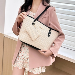 Large beige woven straw tote bag with black leather straps and gold logo for women