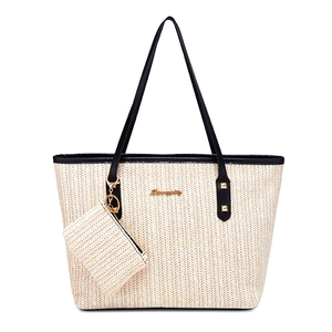 Minimalist straw tote bag with black leather handles and matching small pouch charm