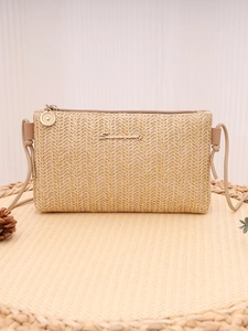 Detailed close-up of Summerly golden logo on woven straw bag with textured pattern