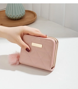 Pink quilted short wallet for women featuring double zippers and a soft pompom charm