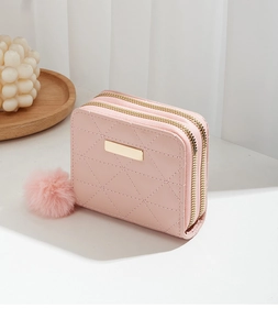 Detailed close-up of pink quilted PU leather wallet with dual zippers and pompom charm