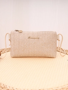 Detail view of woven straw crossbody bag with golden Sunnycity logo and zipper closure