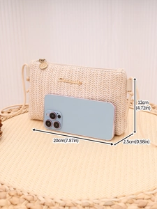Detail view of woven straw crossbody bag with size scale next to a mobile phone