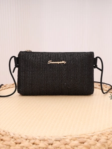 Detail of black straw woven crossbody bag with gold metal logo and zipper closure
