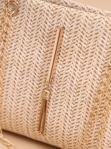 Detailed close-up of beige woven texture and decorative gold fringe tassel on bag