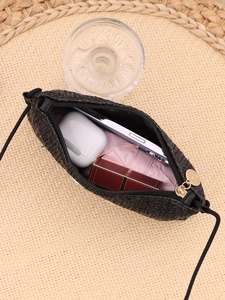 Detail view of black woven crossbody bag showing capacity for phone, earbuds and lipstick