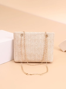 Detail of beige woven straw bag featuring chic herringbone pattern and gold chain strap