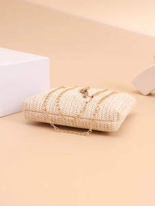 Detail of woven straw clutch bag with golden chain strap and metallic buckle on props