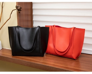Sacs cabas minimalistes en cuir noir et rouge orangé exposés sur une étagère