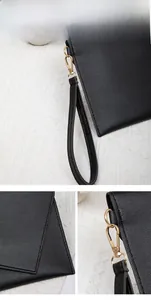 Detail of black leather clutch showing litchi texture and golden metal hook hardware
