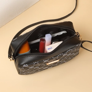Dettaglio della borsa a tracolla nera in PU con cuori che mostra capienza e cerniera dorata