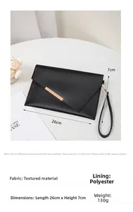 Detail of elegant black clutch bag with gold trim, wrist strap and dimensions 26cm x 7cm