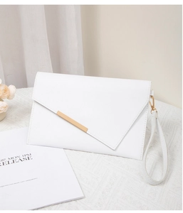 Detail of white envelope clutch with asymmetrical flap and gold metal bar accent