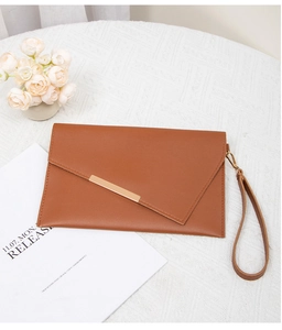 Detail view of caramel brown envelope clutch with gold metal bar and wristlet strap