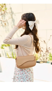 Detail of khaki crossbody bag with unique asymmetrical curved flap design and shoulder strap
