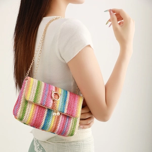Rainbow striped woven crossbody bag with gold chain and pearl ring detail on a model