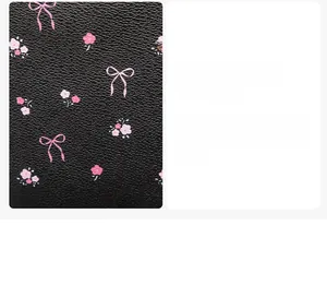 Macro shot of black lychee-textured leather with pink bow and floral prints on a mini backpack