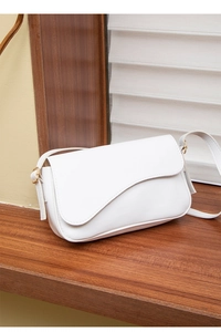 Detail of white PU leather shoulder bag featuring asymmetric wavy flap and gold hardware