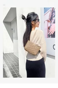 Close-up of khaki quilted leather shoulder bag with elegant gold chain and metal hardware