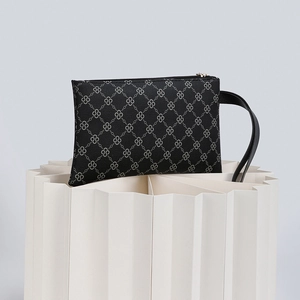 Detail view of black handbag with geometric pattern, zipper closure and leather hand strap