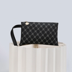 Detail of black monogram clutch bag with gold zipper and stylish wristlet strap
