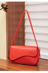 Detail of red crossbody bag featuring scalloped flap design and smooth leather texture