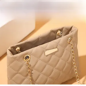 Close-up of khaki quilted leather bag with gold chain eyelets and geometric metal hardware